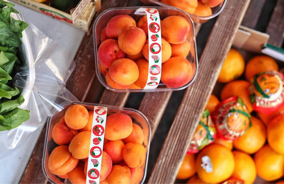 Hand reaching into a crate of ripe peaches